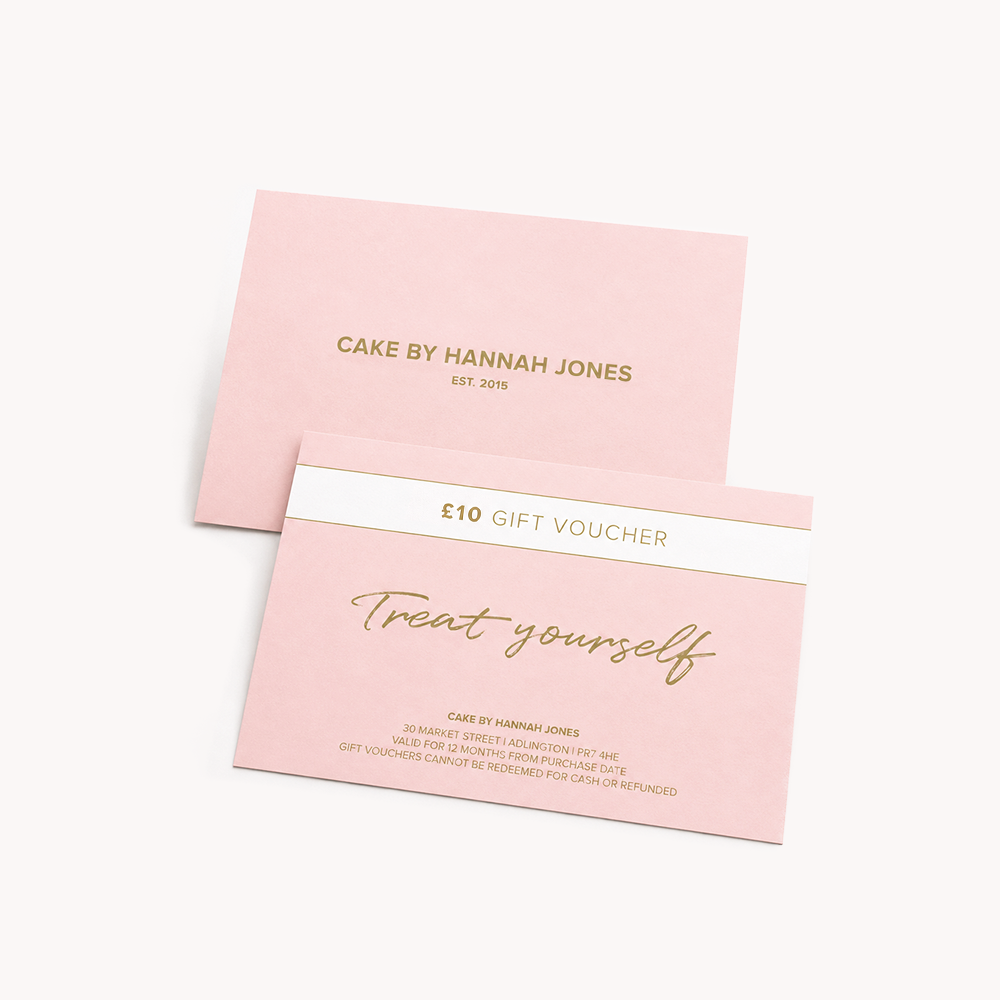 A pink gift voucher card with gold foil text reading '£10 GIFT VOUCHER' and 'Treat yourself,' shown in front of a matching pink backing card printed with 'CAKE BY HANNAH JONES EST. 2015' on a clean white background.